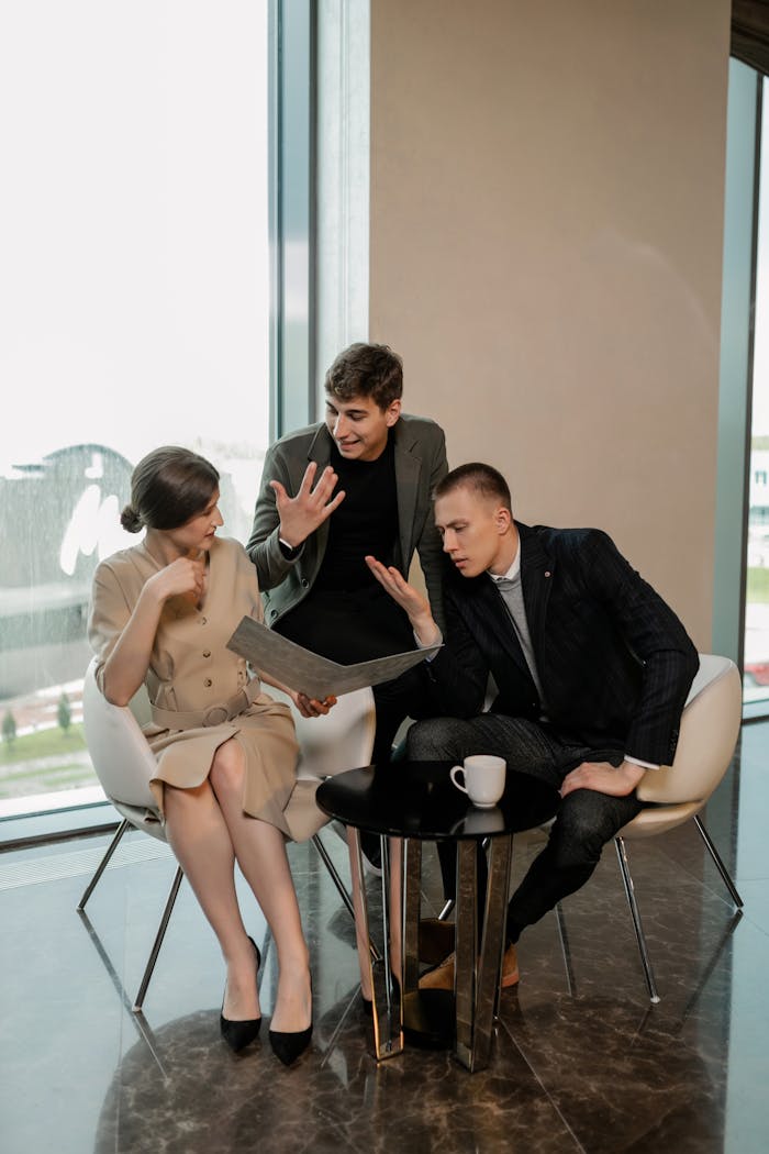 Three colleagues discussing a project in a modern office with large windows.
